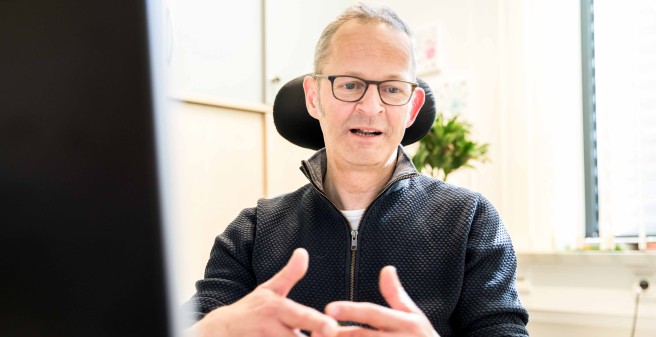 Herr Prof. Buhmann im Gespräch mit einem Patienten, er blickt leicht nach unten auf einen Monitor, der vor ihm auf den Tischsteht. Prof. Buhmann gestikuliert leicht