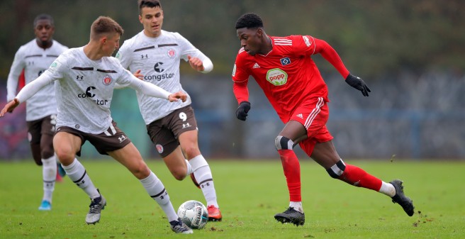 Kraftvoll sprintet der HW U19 Spieler an der gegnerischen Mannschaft vorbei, Grassoden fliegen hoch