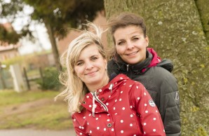 Sandra Fink und ihre Zwillingsschwester Doreen sitzen vor einem großen Baumstamm