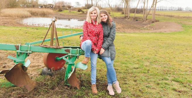 Sandra Fink und ihre Schwester Doreen sitzen auf einer Egge, dahinter eine Weiher