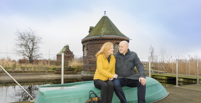 Professor Barbara Schmalfeld und Mann sitzen auf einem umgedrehten grünen Boot im Außengeländer von Kaltehofe