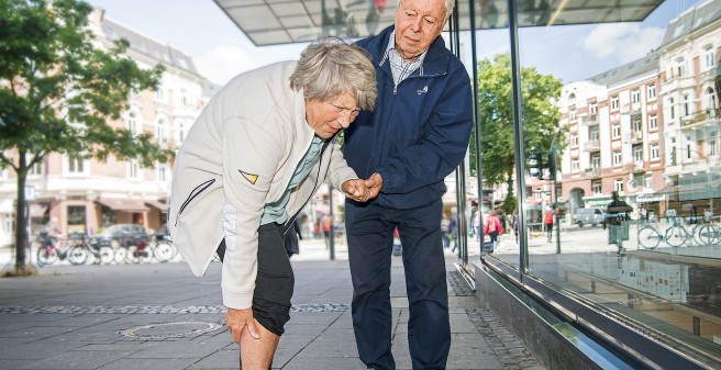 Bild von einer Frau die sich das Knie festhält vor Schmerzen