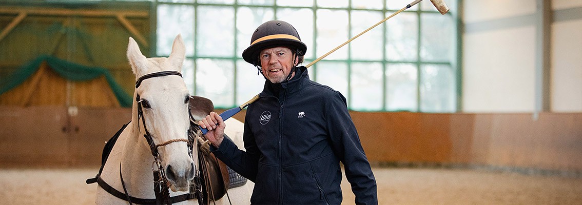 Parkinson - ein Polospieler, der an Parkinson erkrankte mit seinem Pferd in einer Reithalle